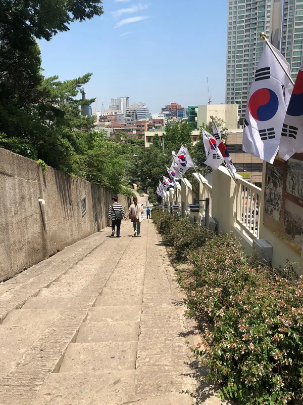 태극기가 걸린 돌담 사이로 오르는 좁은 돌계단 길