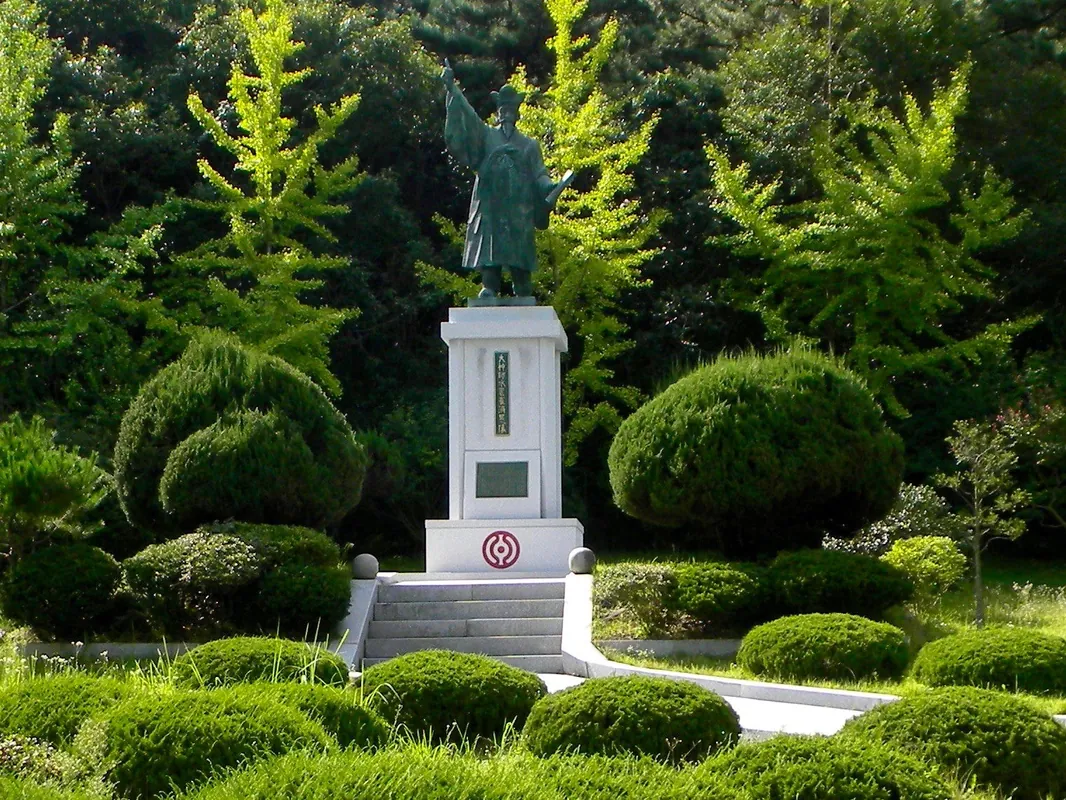푸른 정원수에 둘러싸인 받침대 위 최제우 동상