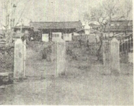 돌기둥 문 너머로 기와집 관아 건물이 보이는 흐릿한 흑백 사진