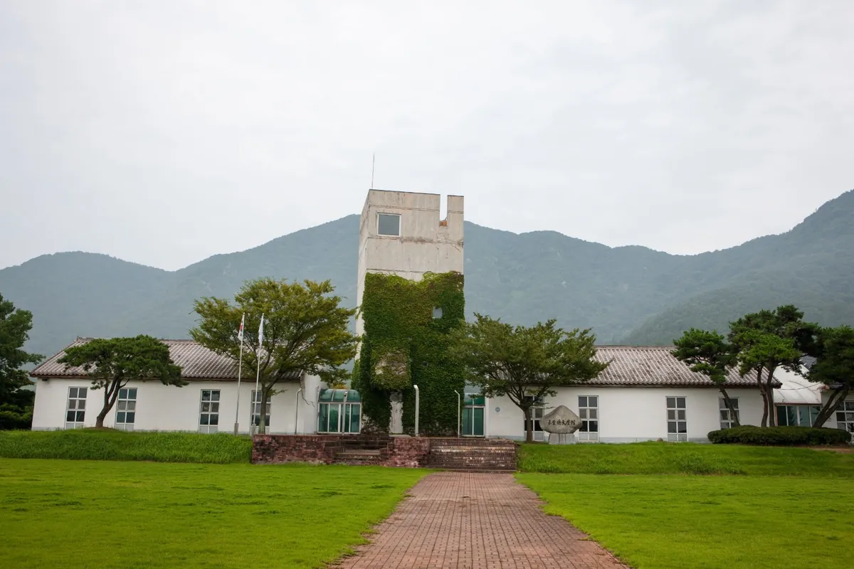 산을 배경으로 넓은 잔디밭 뒤에 선 흰 건물과 탑