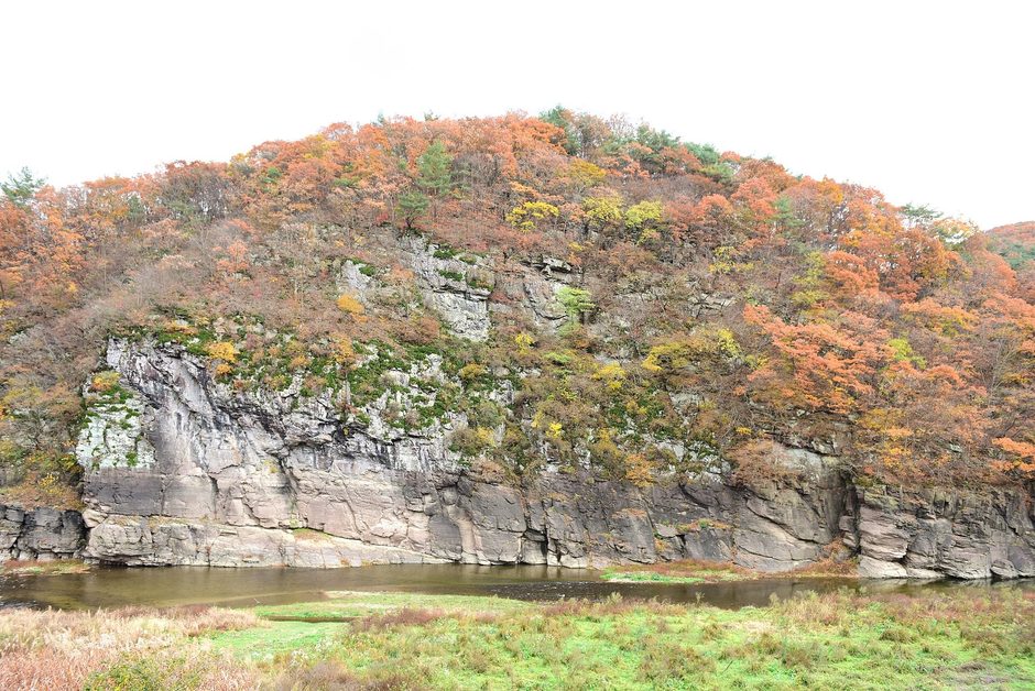 단풍 든 산 아래 물가에 선 대곡천 절벽