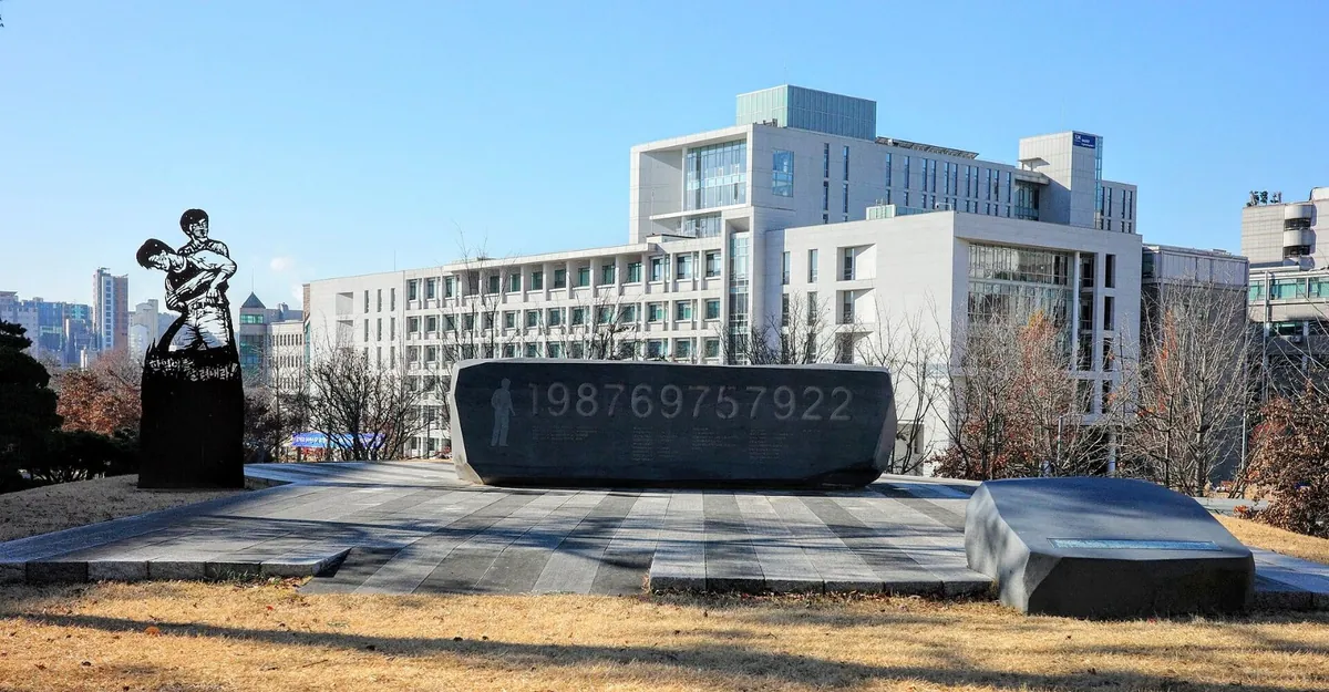 대학 건물 앞 잔디밭에 놓인 검은 기념석과 조각