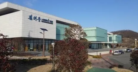 파란 하늘 아래 낮게 펼쳐진 흰 현대식 기념관 건물