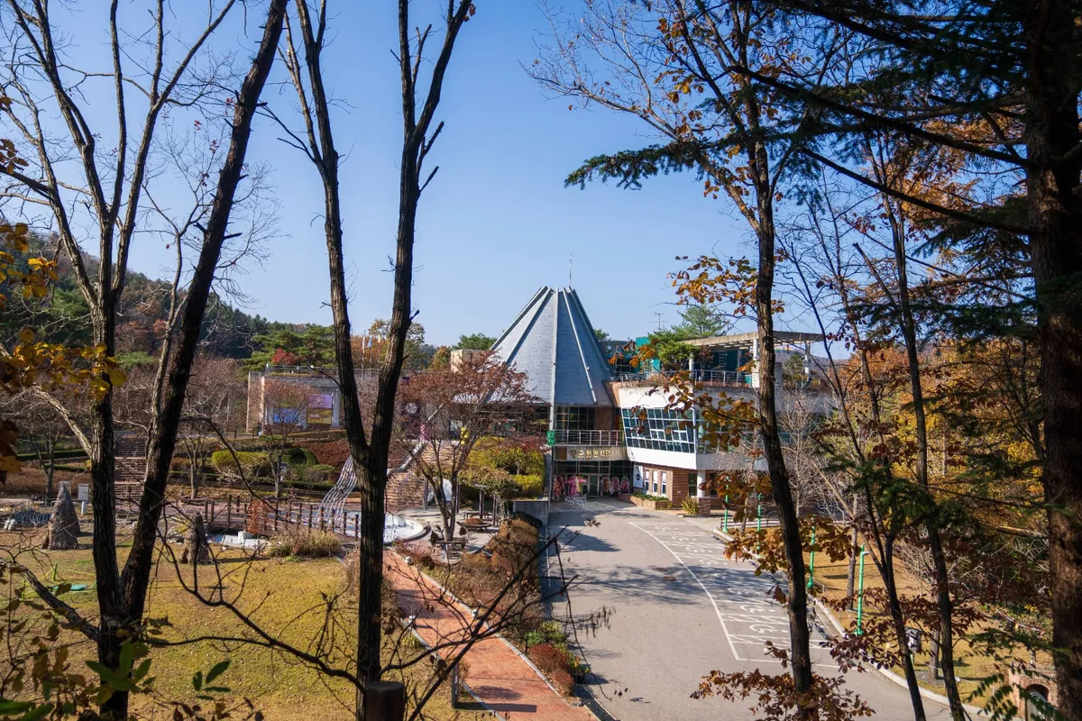 가을 나무 사이로 보이는 뾰족한 지붕의 문학관 건물