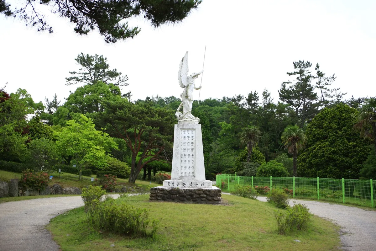 공원 잔디밭 가운데 선 흰 조각 기념탑